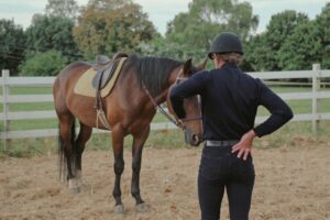 horse rider standing next to their horse - Spinalbackrack
