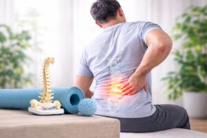 man with lower back pain and highlighted lumbar spine